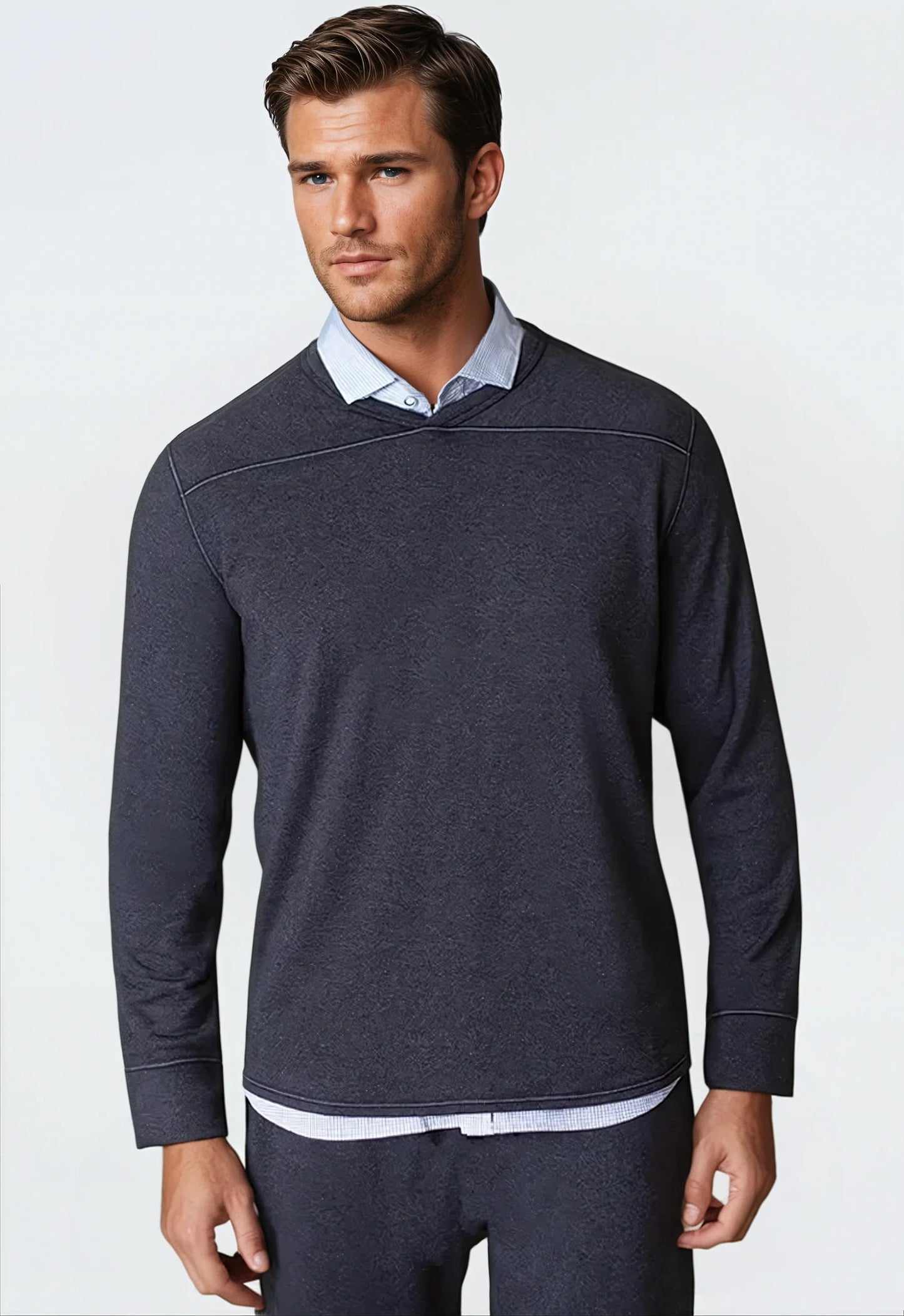 Man wearing a dark blue long-sleeve shirt over a light blue collared shirt on a white background