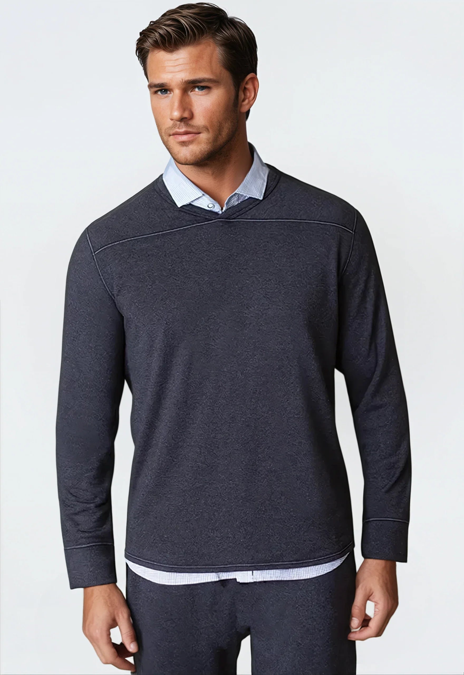 Man wearing a dark blue long-sleeve shirt over a light blue collared shirt on a white background