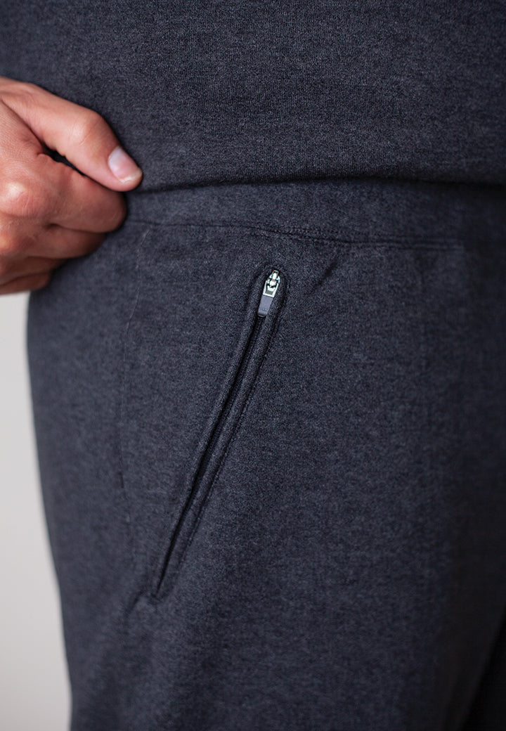 Dark gray sweatpants with a zipper pocket on a light gray background