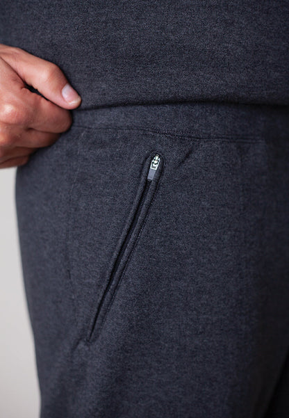 Dark gray sweatpants with a zipper pocket on a light gray background